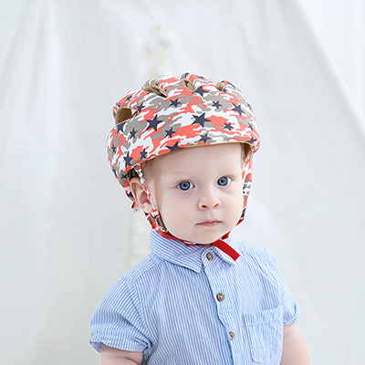 Child wearing a red, gray and white patterned padded cap with red chin ties