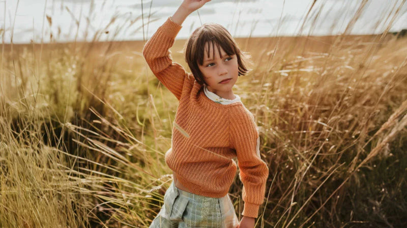 Happy child wearing orange sweater in wheat field - Wobakids comfortable children's clothing