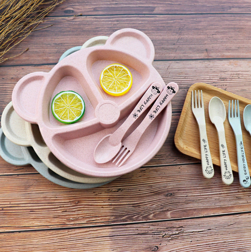 Pink, beige and blue bear-shaped divided plates with matching forks and spoons on a wooden surface