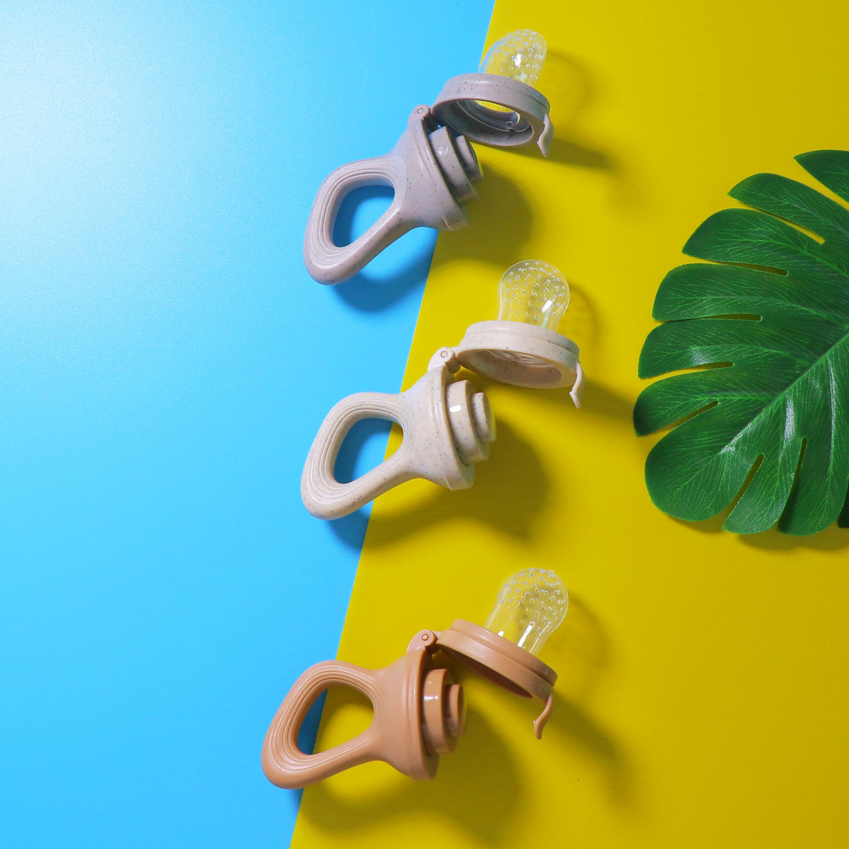 Three baby food feeders opened to show their silicone nipples and hinged handles