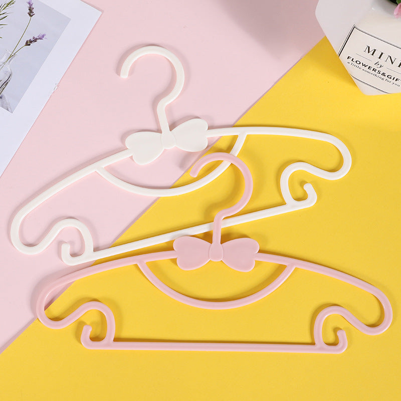 White and pink children's clothes hangers with bow details on a pink and yellow background