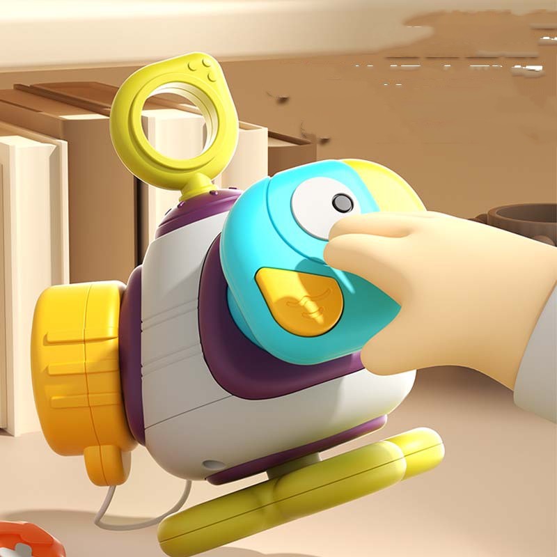 Hand holding the blue bird-shaped piece of a colorful baby activity ball with a green ring handle